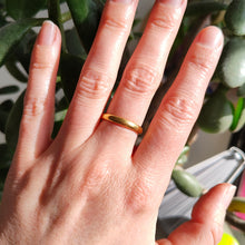 Load image into Gallery viewer, A plain yellow gold wedding band ring, modelled on a hand