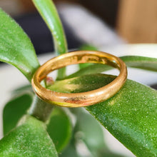 Load image into Gallery viewer, A plain yellow gold wedding band ring, on a green leaf