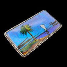 Load image into Gallery viewer, A butterfly wing brooch depicting a sailboat with a palm tree in the foreground, set in silver, on a black background