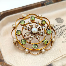 Load image into Gallery viewer, A circular brooch/pendant in yellow gold with peridots and pearls, with a flower to the centre, in an antique box