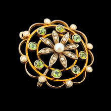 Load image into Gallery viewer, A circular brooch/pendant in yellow gold with peridots and pearls, with a flower to the centre, on a black background
