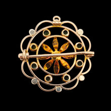 Load image into Gallery viewer, A circular brooch/pendant in yellow gold with peridots and pearls, with a flower to the centre, on a black background