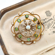 Load image into Gallery viewer, A circular brooch/pendant in yellow gold with peridots and pearls, with a flower to the centre, in an antique box