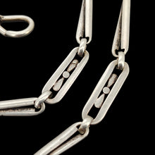 Load image into Gallery viewer, Close-up of fancy links of a silver chain, on a black background