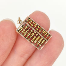 Load image into Gallery viewer, A yellow gold abacus charm, held in a hand