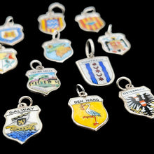 Load image into Gallery viewer, Enamelled silver shield charms depicting various towns, cities and countries, on a black background