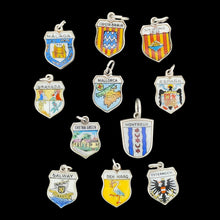 Load image into Gallery viewer, Enamelled silver shield charms depicting various towns, cities and countries, on a black background