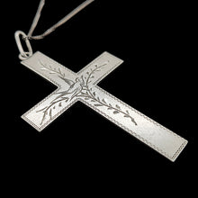 Load image into Gallery viewer, A silver cross pendant engraved with a bird and vines, with a curb link chain, on a black background