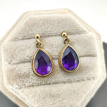 Load image into Gallery viewer, A pair of pear shaped amethyst drop earrings in yellow gold rope edge mounts, in a light-coloured box