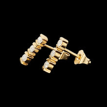 Load image into Gallery viewer, A pair of yellow gold three stone diamond bar set stud earrings, on a black background