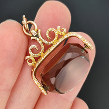 Load image into Gallery viewer, A spinning quartz fob pendant in yellow gold, held in a hand