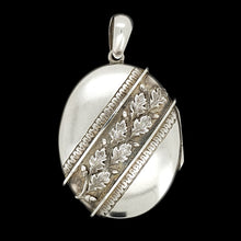 Load image into Gallery viewer, An oval silver locket pendant with acorn and oak leaf detailing, on a black background