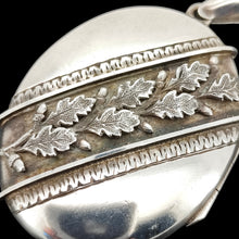 Load image into Gallery viewer, An oval silver locket pendant with acorn and oak leaf detailing, on a black background