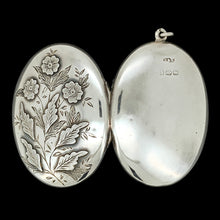 Load image into Gallery viewer, A silver oval locket with flower details, on a black background