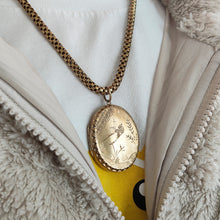 Load image into Gallery viewer, An oval locket with bird engraving with a Venetian link chain in yellow metal, modelled by a woman wearing a Pikachu t-shirt and fluffy jacket