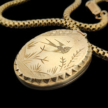 Load image into Gallery viewer, An oval locket with bird engraving with a Venetian link chain in yellow metal, on a black background