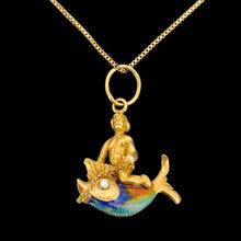 Load image into Gallery viewer, A gold pendant depicting a figure riding a fish, on a black background. The fish has colourful enamel scales in blue, green, and orange. A gold chain connects the figure to the fish. The pendant has a small gold loop at the top for attaching to a chain.