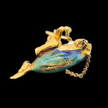 Load image into Gallery viewer, A gold pendant depicting a figure riding a fish, on a black background. The fish has colourful enamel scales in blue, green, and orange. A gold chain connects the figure to the fish. The pendant has a small gold loop at the top for attaching to a chain.
