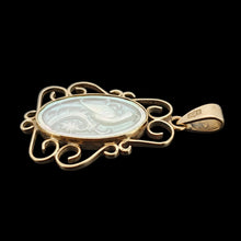 Load image into Gallery viewer, An oval yellow gold and mother of pearl pendant carved with a bird, on a black background