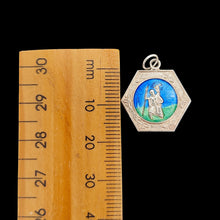 Load image into Gallery viewer, A hexagonal silver Saint Christopher pendant with blue and green enamel, next to a ruler