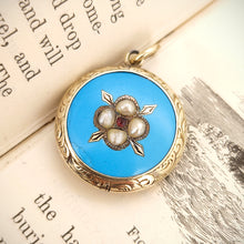 Load image into Gallery viewer, Victorian 9ct Gold Enamel, Pearl and Garnet Glazed Back Pendant sat on the open pages of a book