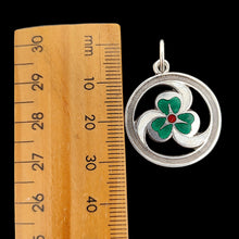 Load image into Gallery viewer, A silver enamel clover triskelion pendant, next to a ruler, on a black background