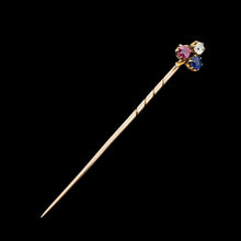 Load image into Gallery viewer, A ruby, sapphire and diamond clover shaped stick tie pin in gold, on a black background