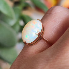 Load image into Gallery viewer, A single stone oval shaped, cabochon cut opal ring in rose gold, modelled on a hand