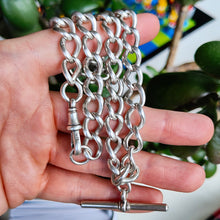 Load image into Gallery viewer, A silver curb link Albert chain with lobster clasp and T-bar, held in a hand
