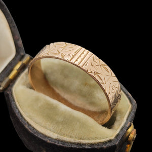 Gold ring with intricate design in an open antique ring box on a black background