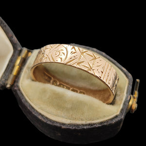 Gold ring with intricate design in an open antique ring box on a black background