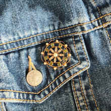 Load image into Gallery viewer, A circular brooch/pendant in yellow gold with peridots and pearls, with a flower to the centre, modelled on a denim jacket
