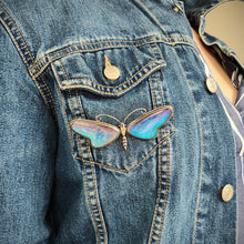 Load image into Gallery viewer, A large blue morpho butterfly wing butterfly brooch in silver, modelled on a denim jacket
