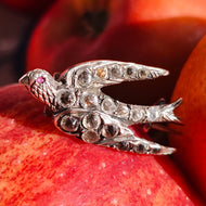 An antique swallow bird brooch in silver with paste stones, resting on apples