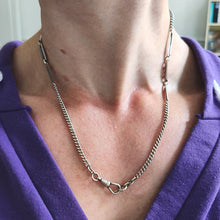 Load image into Gallery viewer, A silver curb and fancy link chain necklace with a lobster claw clasp, modelled by a woman wearing a purple top
