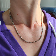 Load image into Gallery viewer, A silver curb and fancy link chain necklace with a lobster claw clasp, modelled by a woman wearing a purple top

