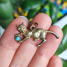 Load image into Gallery viewer, A yellow metal cat playing with a blue ball charm, held in a hand
