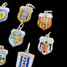 Load image into Gallery viewer, Enamelled silver shield charms depicting various towns, cities and countries, on a black background
