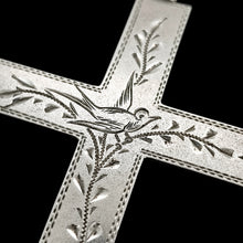 Load image into Gallery viewer, A silver cross pendant engraved with a bird and vines, close-up, on a black background
