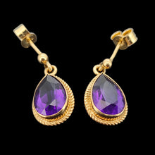 Load image into Gallery viewer, A pair of pear shaped amethyst drop earrings in yellow gold rope edge mounts, on a black background
