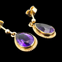 Load image into Gallery viewer, A pair of pear shaped amethyst drop earrings in yellow gold rope edge mounts, on a black background
