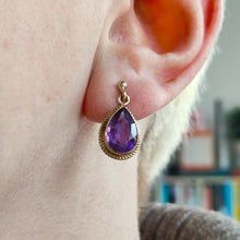 Load image into Gallery viewer, A pear shaped amethyst drop earring in yellow gold rope edge mount, modelled in an ear
