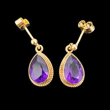 Load image into Gallery viewer, A pair of pear shaped amethyst drop earrings in yellow gold rope edge mounts, on a black background
