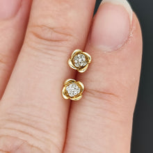 Load image into Gallery viewer, A pair of yellow gold diamond stud earrings, held in a hand
