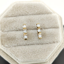 Load image into Gallery viewer, A pair of yellow gold three stone diamond bar set stud earrings, in a light-coloured box
