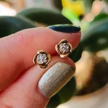 Load image into Gallery viewer, A pair of yellow gold diamond stud earrings, held in a hand
