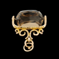 A spinning quartz fob pendant in yellow gold, on a black background