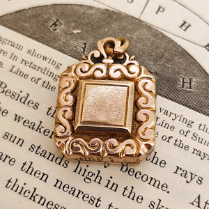 Antique Rolled Gold Ornate Locket Pendant shown from the front, on an illustrated book background