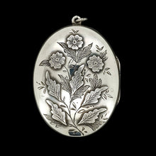Load image into Gallery viewer, A silver oval locket with flower details, on a black background
