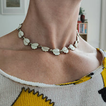 Load image into Gallery viewer, A white enamel leaf necklace in silver gilt modelled by a woman
